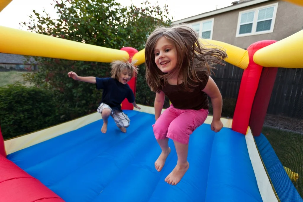 Kids jumping safely inside a bounce house following bounce house safety rules
